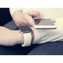 une personne porte une montre connectée et regarde son smartphone