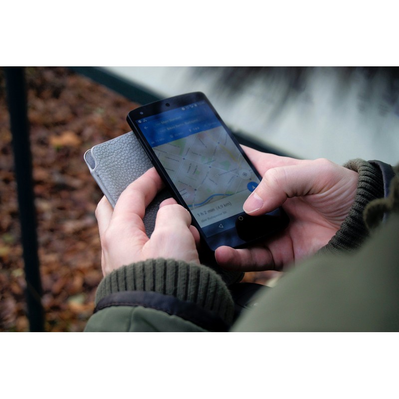 Une personne tenant un portable vérifie sa géolocalisation