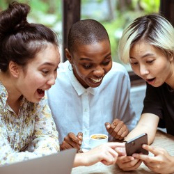 3 personnes rient devant un smartphone