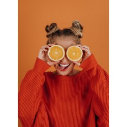 Femme tenant deux tranches d\'orange devant ses yeux en tirant la langue