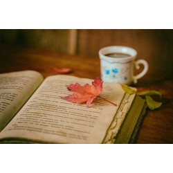 Livre ouvert sur une table en bois, décoré d\'une feuille d\'automne, posé à côté d\'une tasse de café.