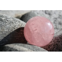 Une sphère en quartz rose sur des galets