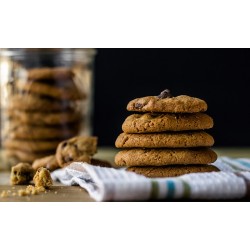 Empilement de cookies déposés sur un torchon avec d\'autres cookies dans un bocal, dressés sur une table.