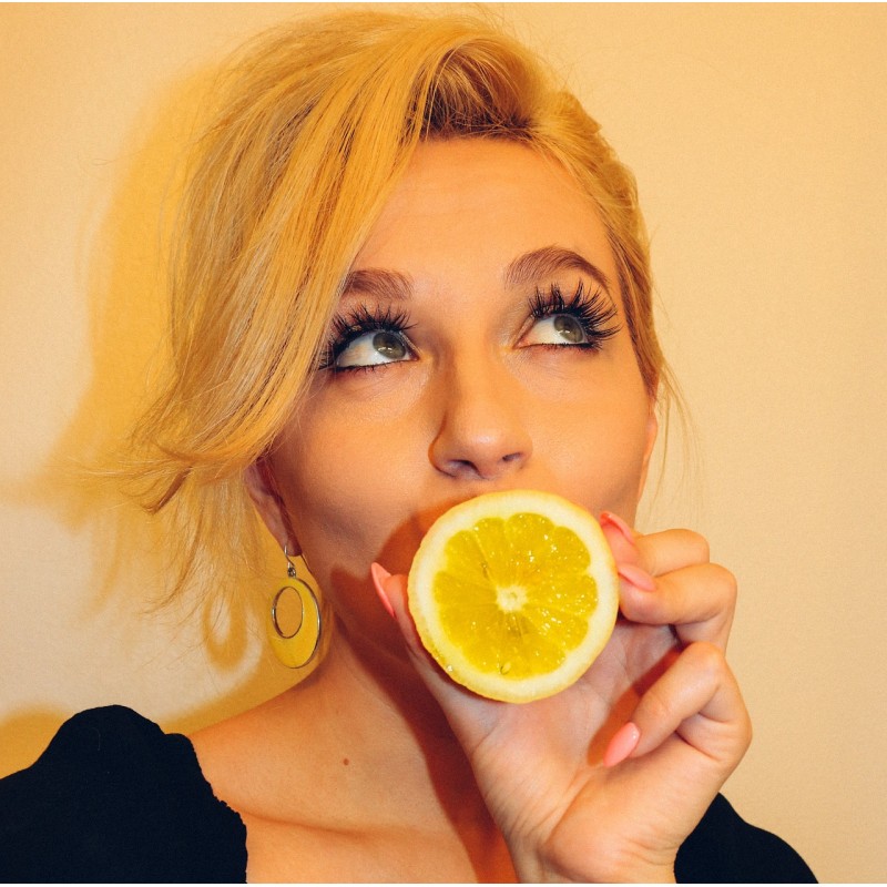 femme avec des faux cils et un citron dans la main