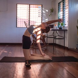 Une femme pratiquant la posture de yoga du chameau chez elle