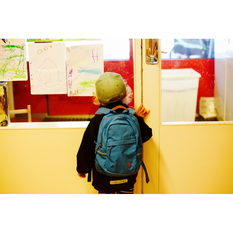 Enfant avec cartable devant la salle de classe