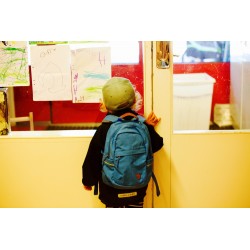Jeune enfant avec cartable devant la porte vitrée d\\\'une salle de classe