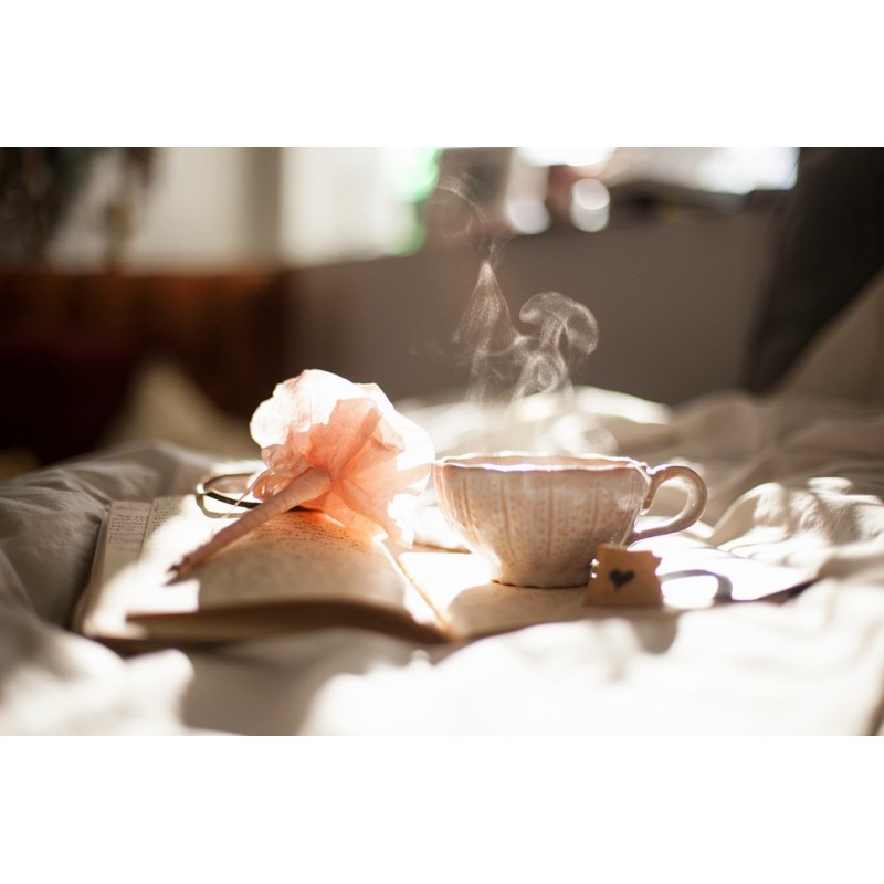Une tasse de thé fumante près d\'un livre et d\'une fleur