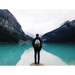 un touriste vu de dos face à un lac de montagne