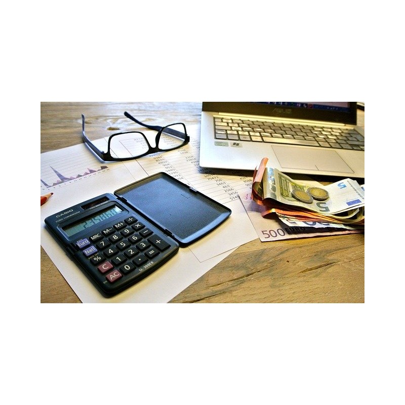 Calculatrice, documents pour les impôts, ordinateur et monnaie en euros