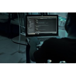 Homme tapant des lignes de code sur un ordinateur portable avec un fond d\'écran sombre.